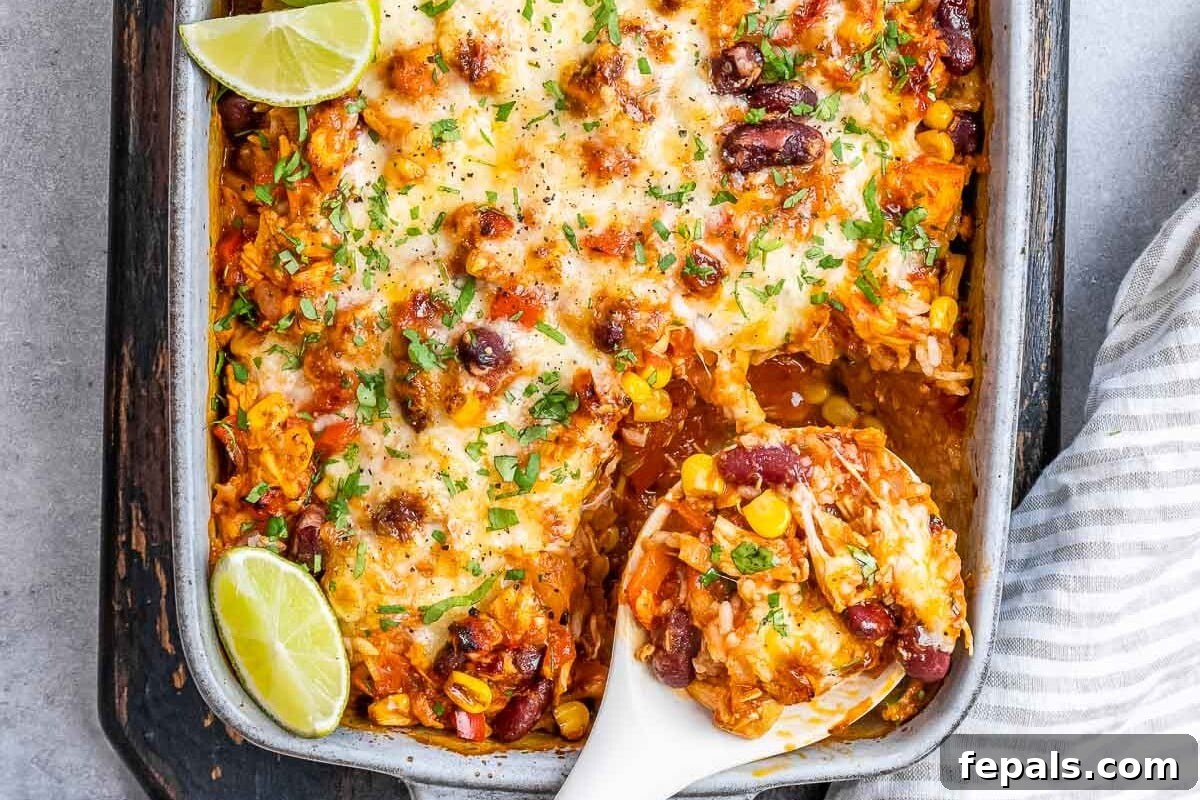 A golden-brown Mexican chicken casserole, fresh from the oven, served in a white baking dish with a rustic linen background.