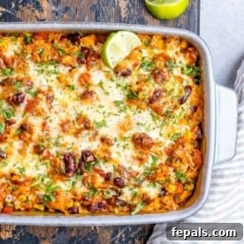 White casserole dish with Mexican chicken and rice casserole topped with melted cheese.