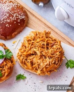 Effortless Slow Cooker BBQ Pulled Chicken 16 Overhead view of shredded BBQ chicken piled high on an open sandwich bun.