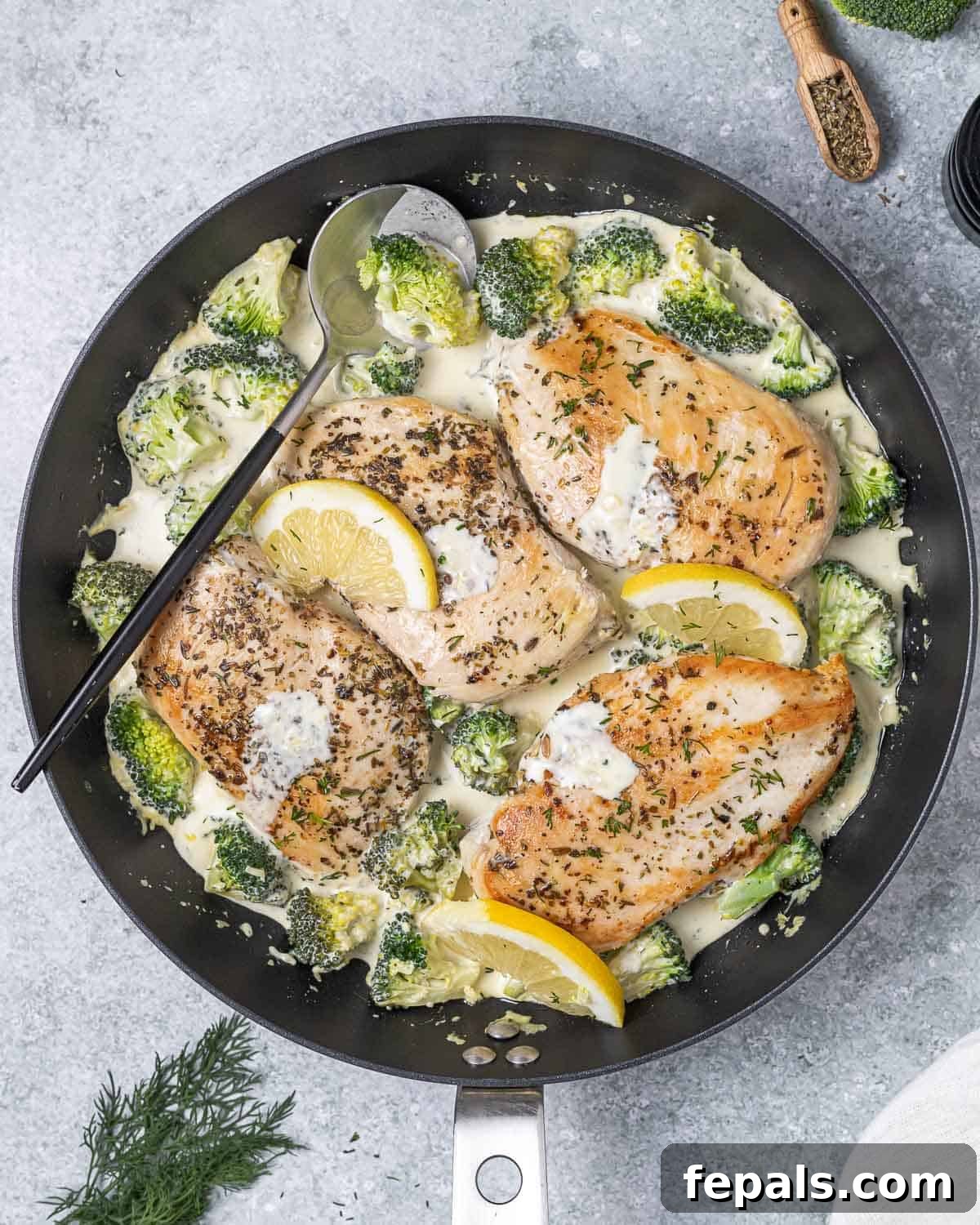 A skillet with creamy seared chicken breast with broccoli.