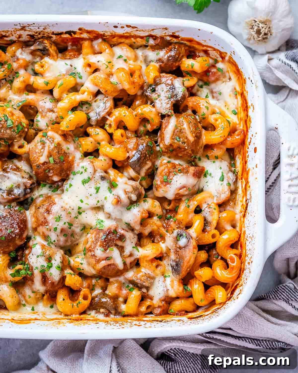 Effortless Meatball Bake 2 Dump and bake meatball casserole in a white casserole dish, garnished with fresh parsley.