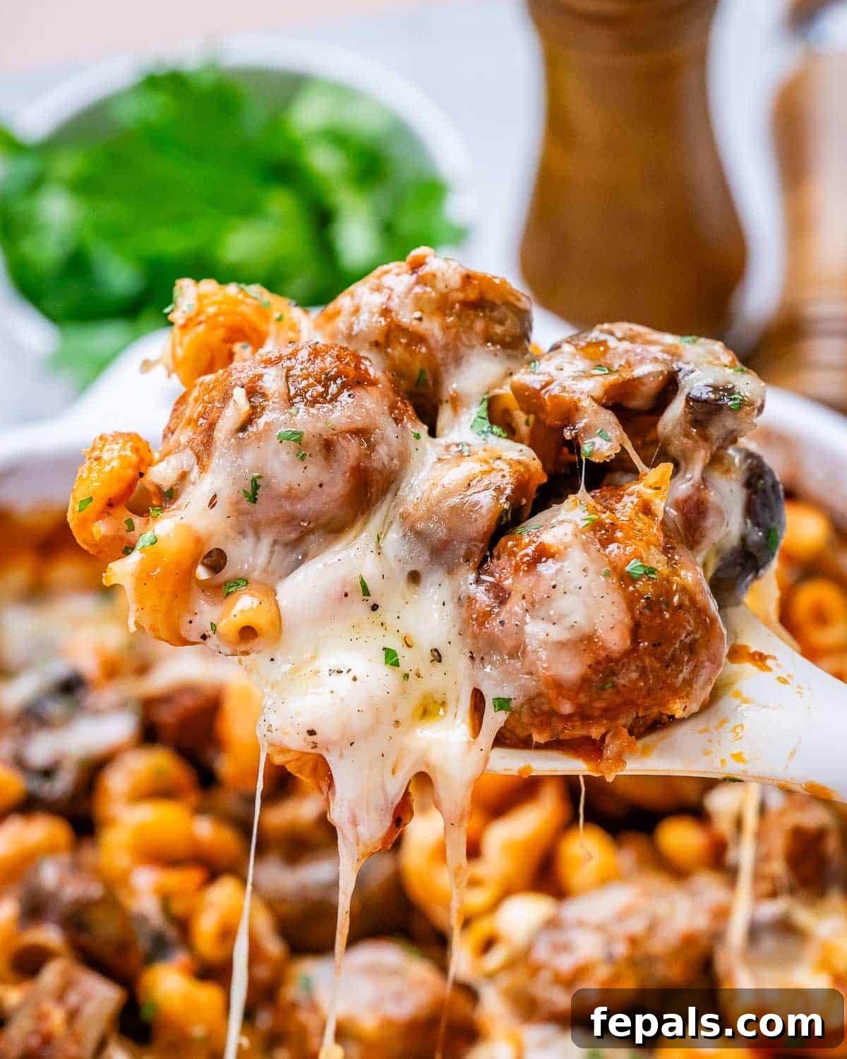 Effortless Meatball Bake 7 A close-up image of a spoonful of dump and bake meatball casserole, showing pasta, meatballs, and melted cheese.
