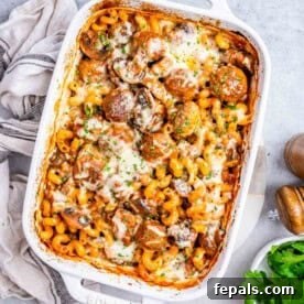 A casserole with meatball and pasta with tomato sauce and veggies.