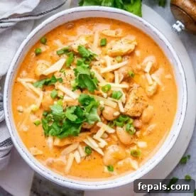 A bowl with crack chicken chili topped with shredded cheese and cilantro, ready to eat.