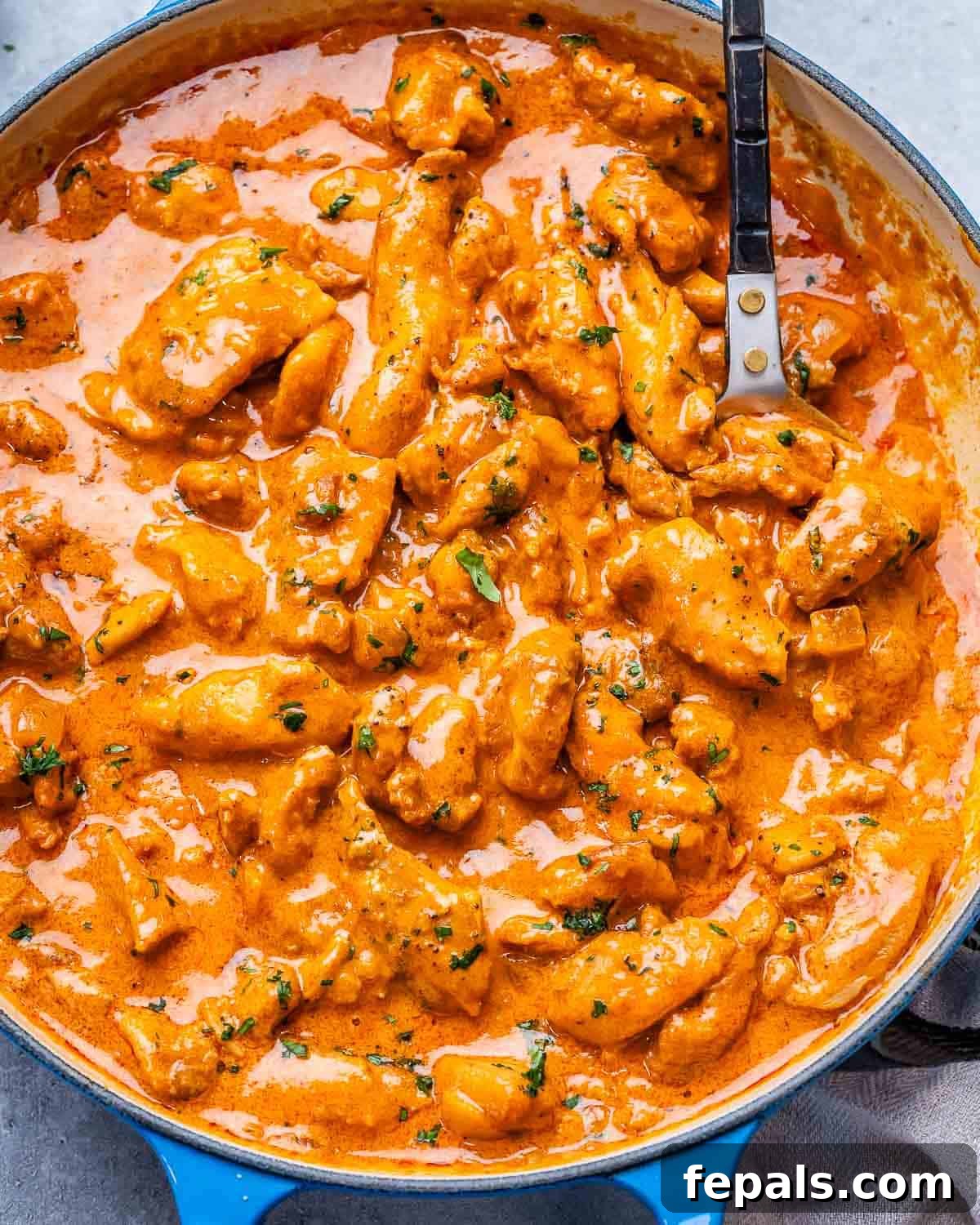 Creamy Hungarian Chicken 2 A close up of chicken paprikash in a blue skillet, showcasing the rich red sauce and tender chicken pieces, ready to be served.