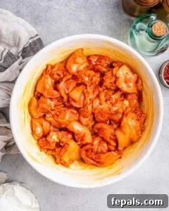 Seasoning chicken pieces in a bowl for Chicken Paprikash.