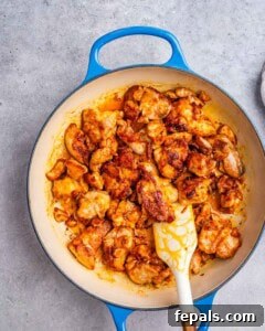 Searing seasoned chicken thighs in a skillet until golden brown.