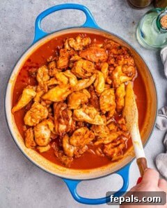 Simmering chicken in the rich paprika sauce until tender.
