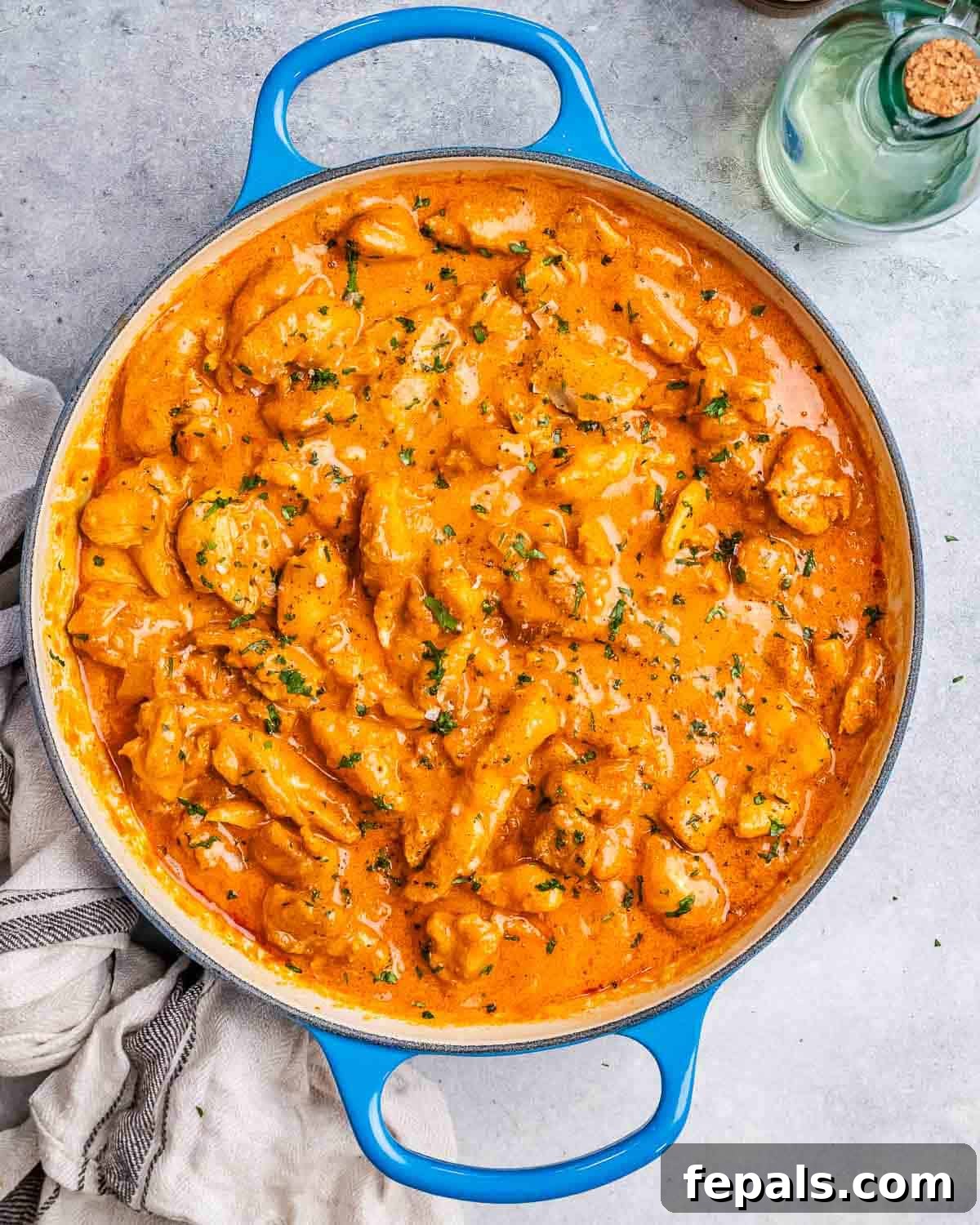 Creamy Hungarian Chicken 7 A vibrant blue skillet filled with creamy chicken paprikash, ready to be served, set against a grey kitchen towel, highlighting its comforting appeal.