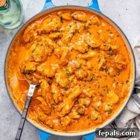 A skillet with chicken bites cooked in a creamy orange paprika sauce, a perfect example of Chicken Paprikash.