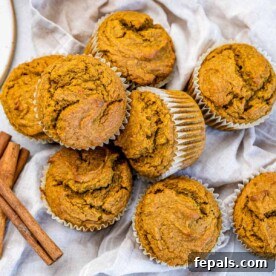 Autumnal pumpkin muffins artfully arranged on a napkin, with fragrant cinnamon sticks beside them for a cozy visual.