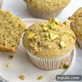 A beautifully presented green pistachio muffin resting on a clean white plate, highlighting its unique color and texture.