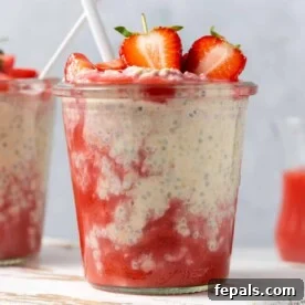 A side shot of a jar with creamy overnight oats, beautifully layered with blended fresh strawberries, creating a vibrant and tempting breakfast.