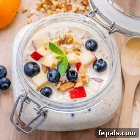 A mason jar filled with Princess Diana's overnight oats, elegantly topped with finely chopped apples, fresh blueberries, and crunchy walnuts, ready for a nutritious breakfast.