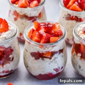 A side shot of a jar brimming with strawberry cheesecake overnight oats, topped generously with fresh, vibrant strawberries, creating a visually appealing and delicious breakfast.