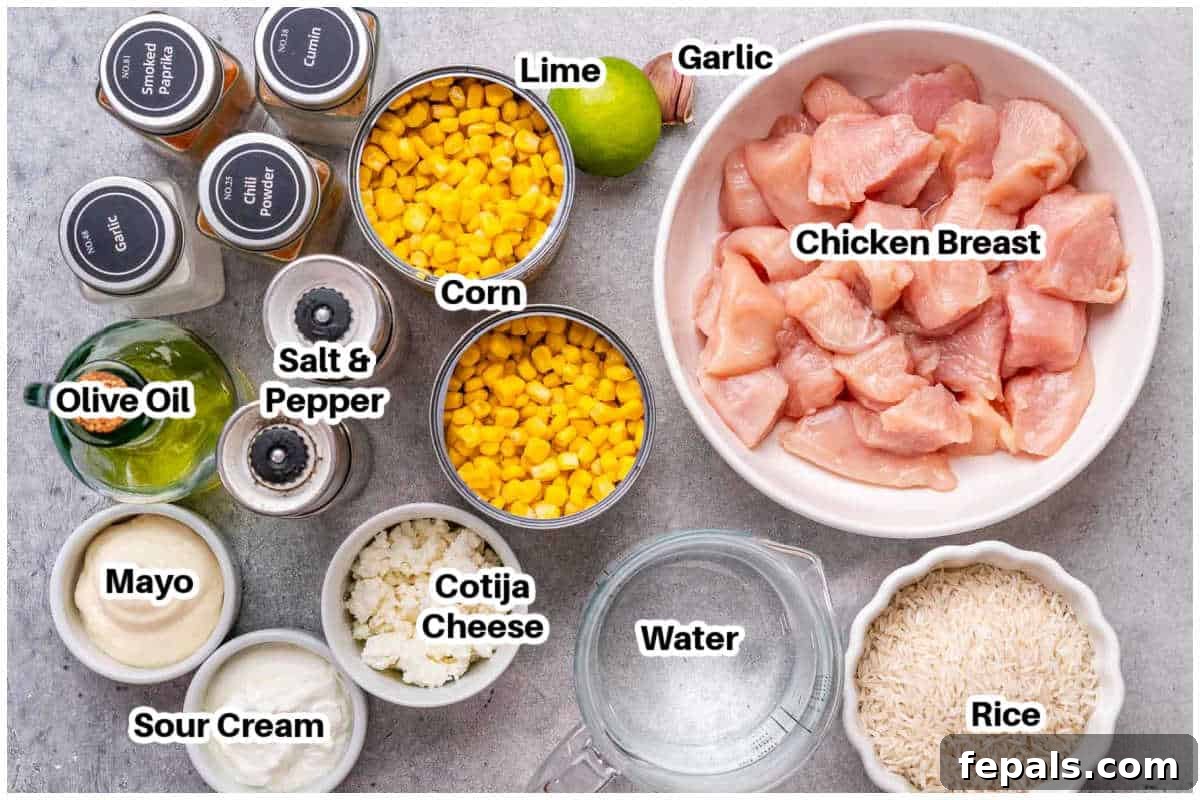 A flat lay photograph showcasing all the fresh ingredients needed to prepare the street corn chicken rice bowl, including chicken breast, corn kernels, lime, garlic, mayonnaise, sour cream, and a selection of vibrant spices.