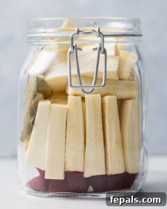 Beets and turnips are carefully added to a clean mason jar, along with a bay leaf, ready for the brine.