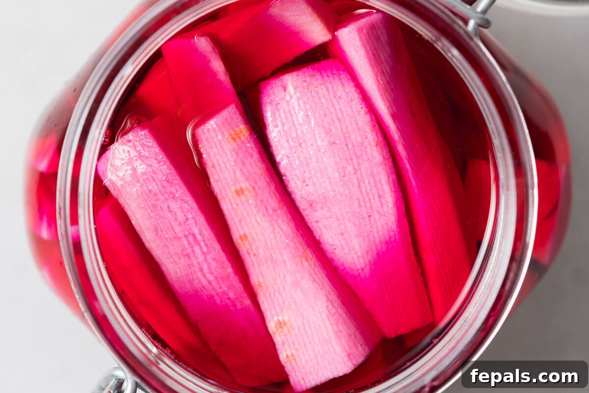 A beautifully arranged glass jar showcasing perfectly pickled pink turnips, ready for serving.