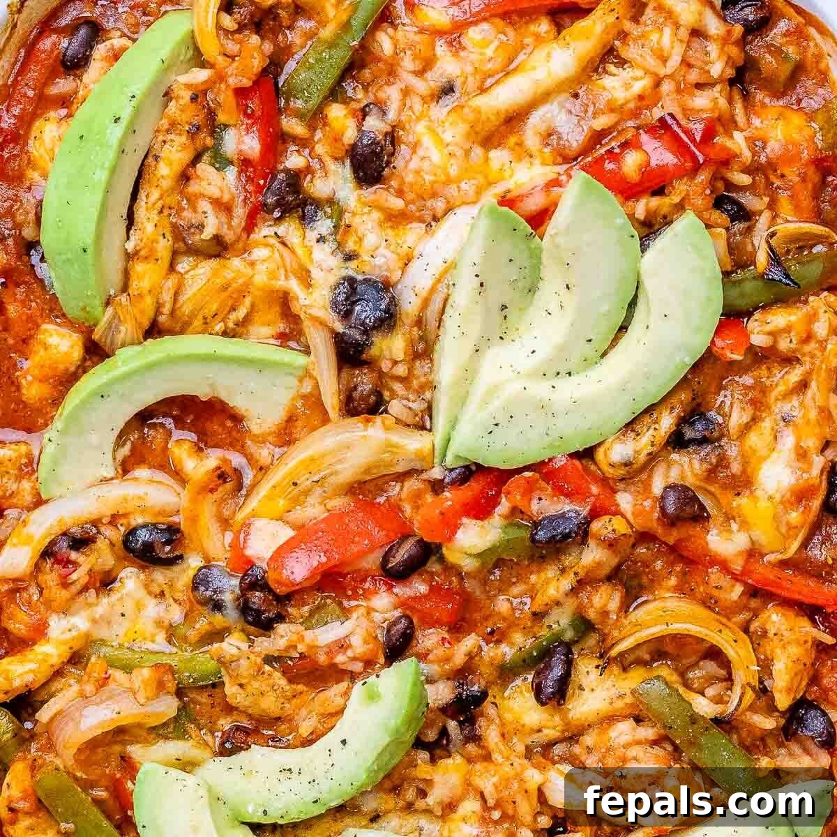 A close-up shot of a steaming chicken fajita casserole in a baking dish, adorned with fresh avocado slices, highlighting its mouth-watering texture.