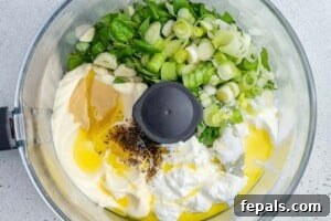 ingredients for the green goddess dressing placed in a food processor to be blended.