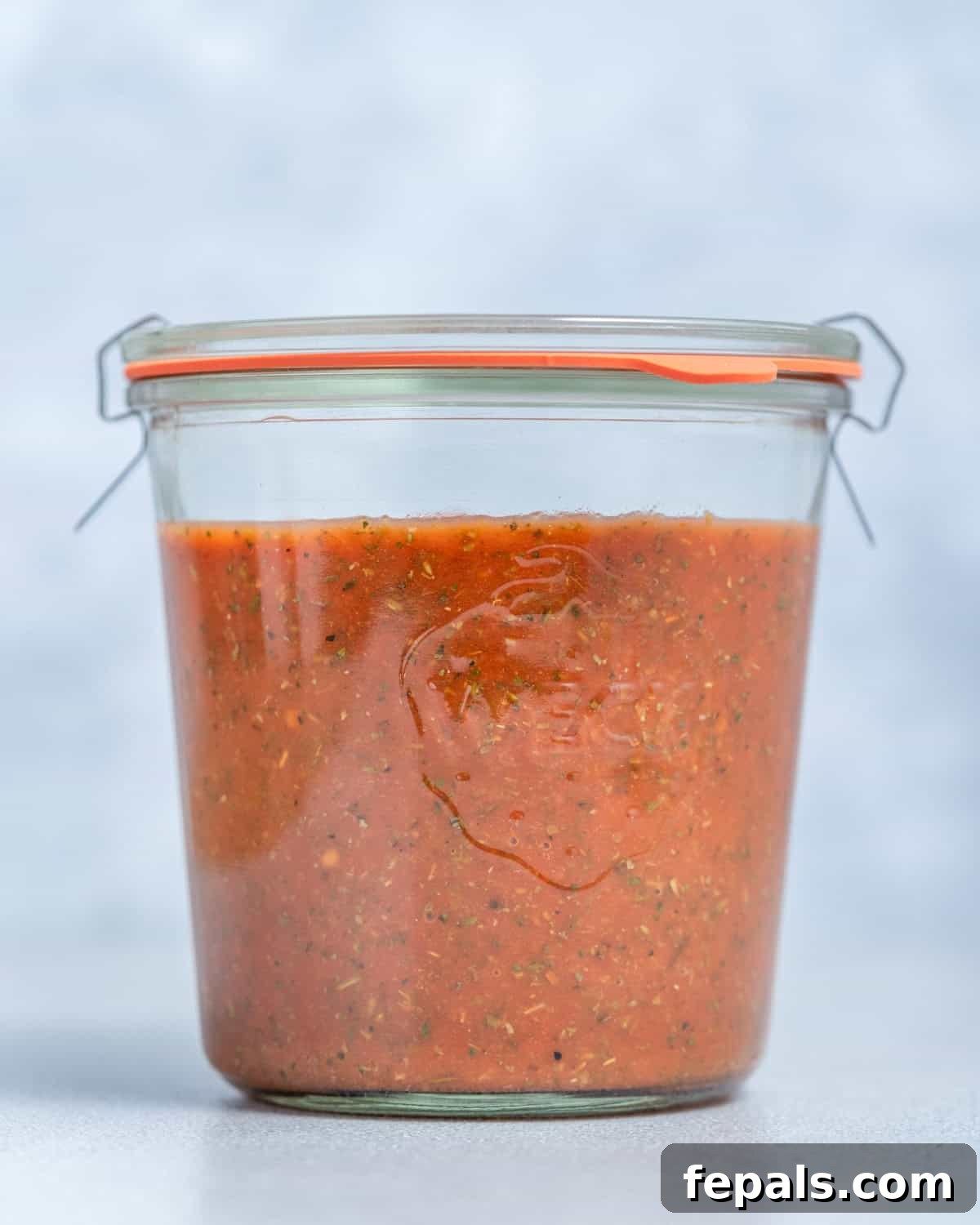 A beautifully presented jar of homemade pizza sauce, ready to be used, highlighting its rich color and smooth texture.
