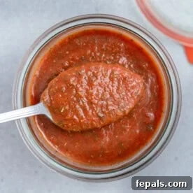 a jar full of pizza sauce with a spoonful of sauce over the jar.