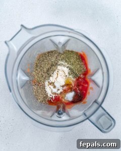 Ingredients for homemade pizza sauce being added to a blender.