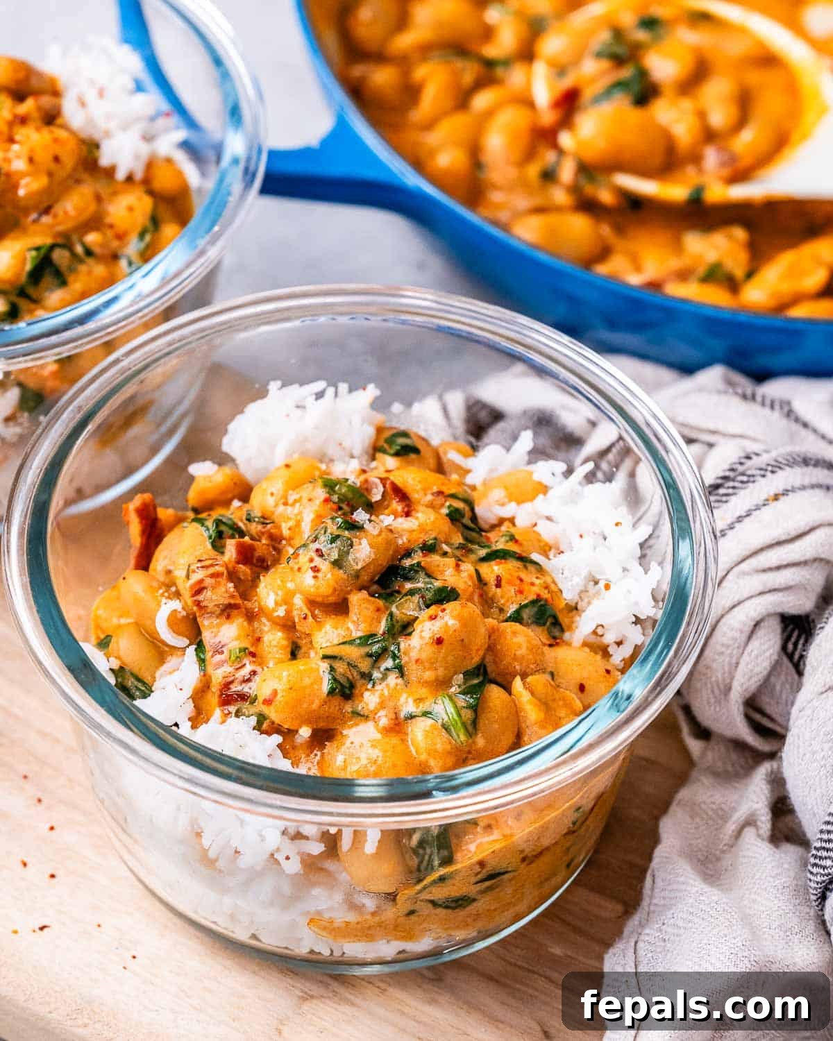 The Butter Bean Proposal 2 A bowl of fluffy white rice topped generously with Marry Me Butter Beans, garnished with fresh herbs, showcasing a vibrant and inviting meal.