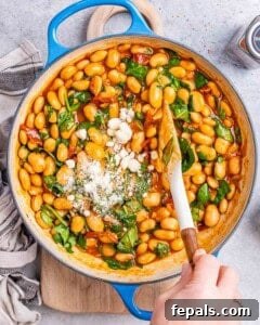 Fresh spinach and parmesan cheese added over the beans in skillet.