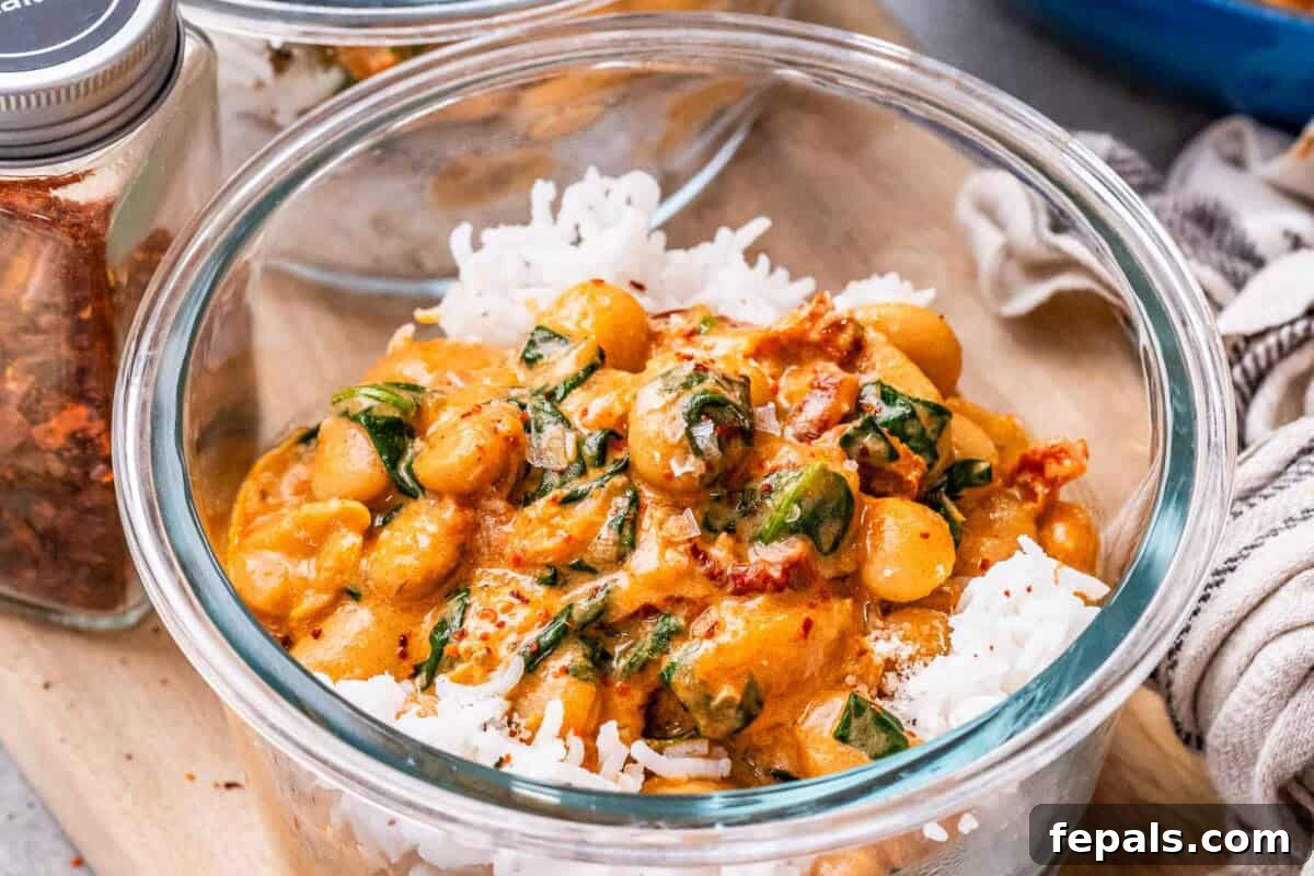 The Butter Bean Proposal 6 A clear glass bowl filled with fluffy white rice, topped with a generous serving of creamy Marry Me Butter Beans, garnished with fresh basil leaves.
