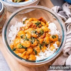 A meal prep glass bowl with marry me butter beans served over white rice, ready to be stored or eaten.