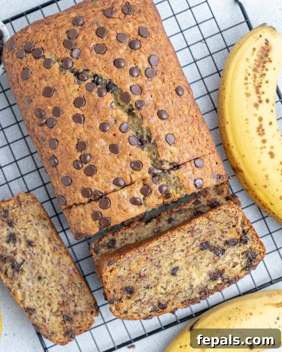 Nutty Browned Butter Banana Loaf 2 A freshly baked loaf of Browned Butter Banana Bread cooling on a wire rack, with one half already sliced and showing its soft, moist interior.