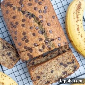 A beautiful loaf of browned butter banana bread on a wire rack, with a slice taken out to show its moist texture.