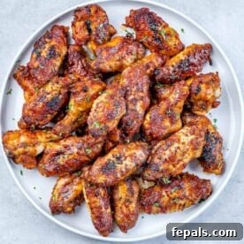 Baked honey garlic chicken wings on a round white plate, glistening with a sweet and savory sauce.
