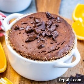 Valentine's Day Recipes for Grown-Ups 19 Baked Chocolate Soufflé in a white ramekin, sprinkled with chopped chocolate pieces and placed beside fresh orange slices.