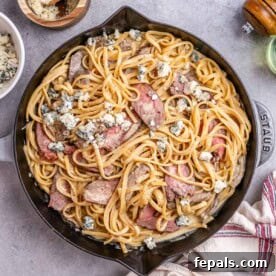 Valentine's Day Recipes for Grown-Ups 5 pasta with steak slices in a skillet topped with crumbled blue cheese.