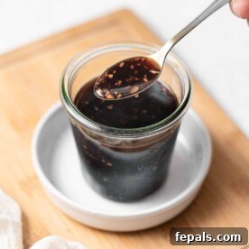 Side view of homemade teriyaki sauce in a jar with a spoonful of sauce, ready to be used.