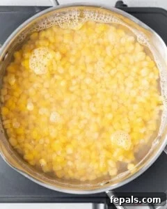 Frozen corn being cooked on a stove.