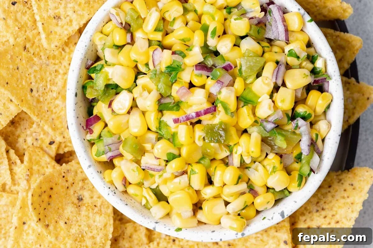 A beautifully arranged bowl of corn salsa, surrounded by golden tortilla chips, inviting you to dig in.