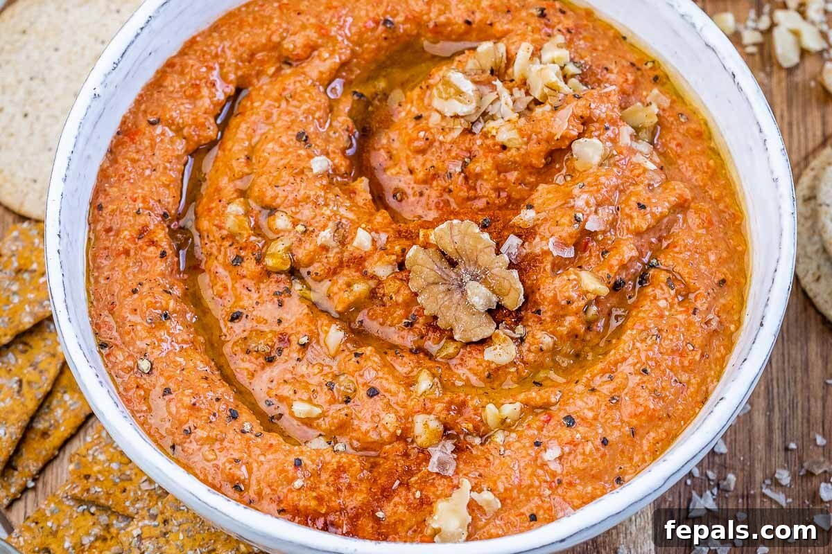 A beautifully presented bowl of homemade Muhammara, garnished with a swirl of olive oil and a few whole walnuts, ready to be served.