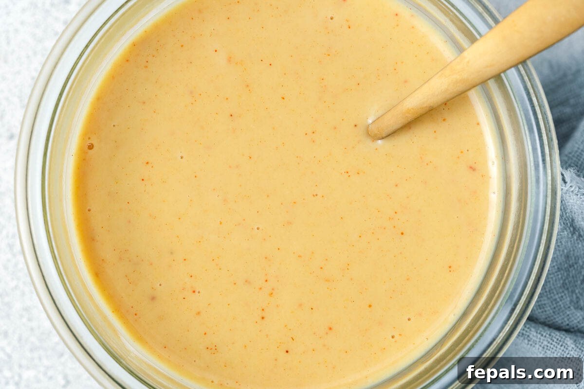 Honey mustard sauce in a bowl with a spoon in it, ready to be served.