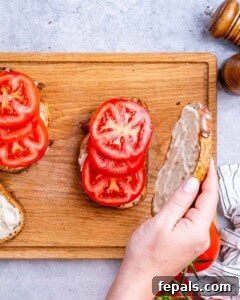assembling the sandwich with the sliced tomatoes on the toast.