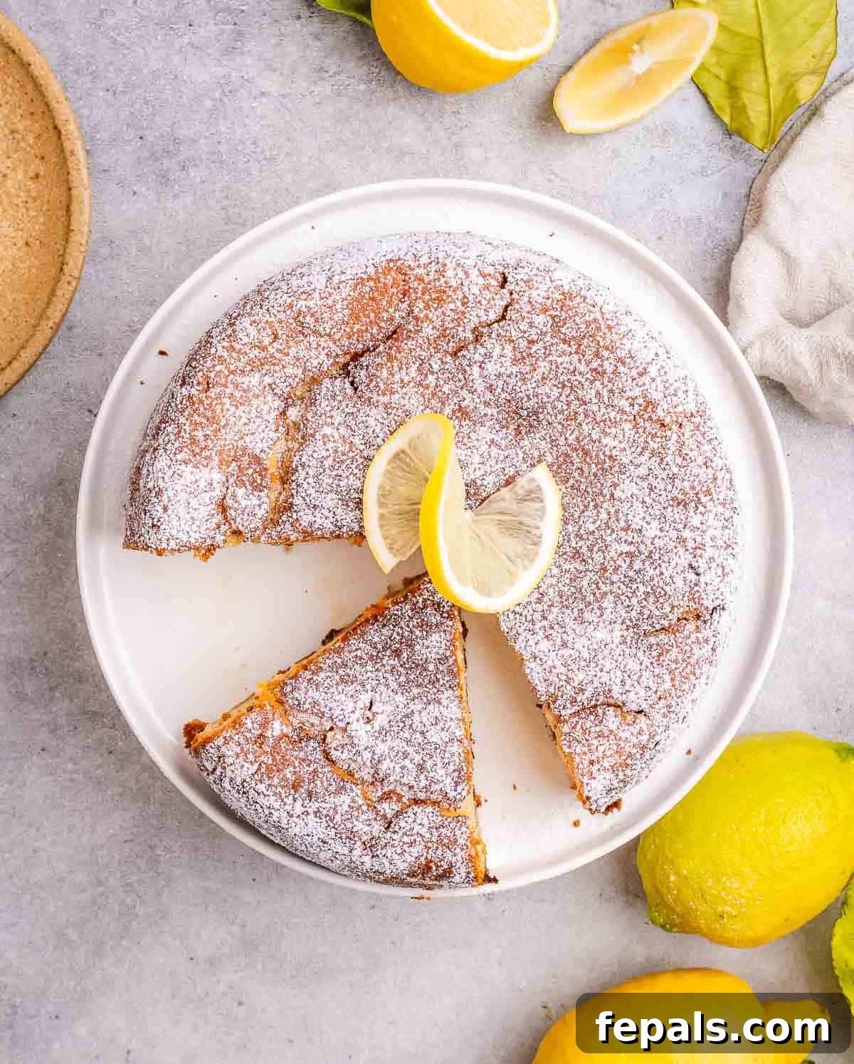 A beautifully presented lemon ricotta cake on a plate with a slice already removed, showcasing its moist texture.