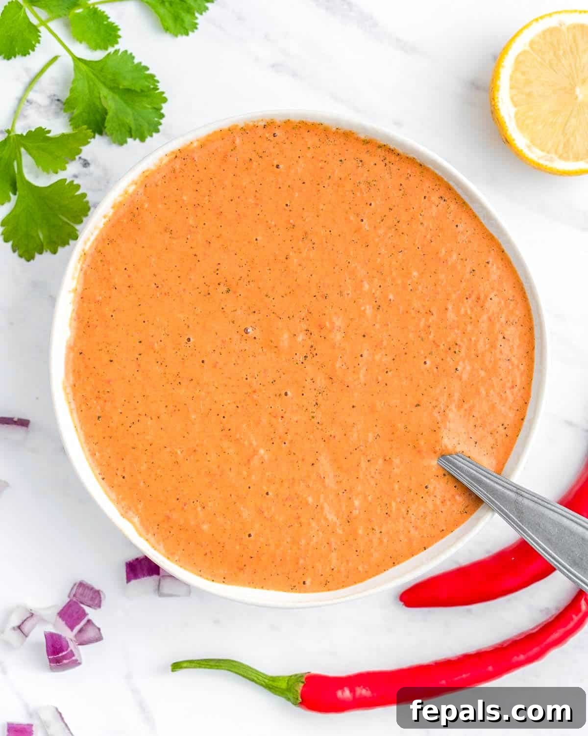 Spicy Homemade Peri Peri Sauce 2 A vibrant bowl of homemade Peri Peri Sauce with a spoon, ready to be served.