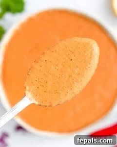 A bowl with peri peri sauce and a spoonful over the bowl.