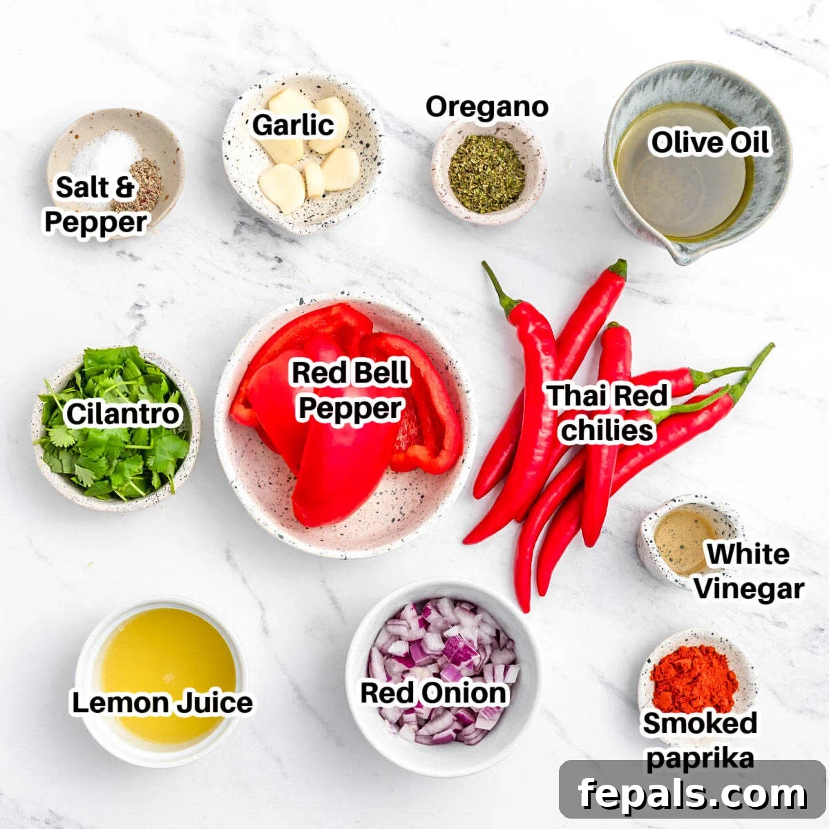 Spicy Homemade Peri Peri Sauce 3 A collection of fresh ingredients laid out on a board, including red bell peppers, chilies, garlic, onion, cilantro, and spices, ready to make peri peri sauce.