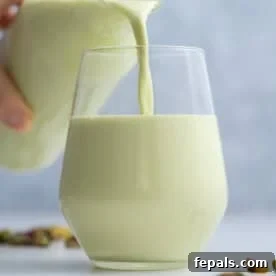 Pouring pistachio milk from a bottle into a cup.