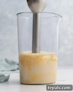 Immersion blender continuing to blend, with the mayonnaise now mostly thick and smooth inside the jar.