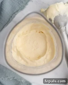 Close-up of thick, creamy homemade mayonnaise in a tall glass mixer, showing the smooth, emulsified texture after blending, with an immersion blender lying next to it with mayonnaise on the end.