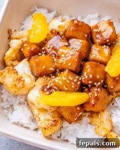 Crispy Orange Tofu 13 A close-up image of crispy orange tofu and cauliflower with rice in a white bowl.